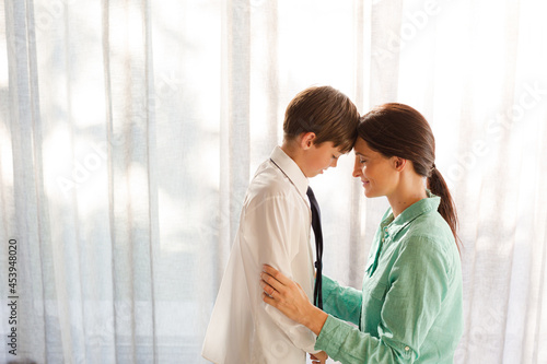 Mother and son touching foreheads at window