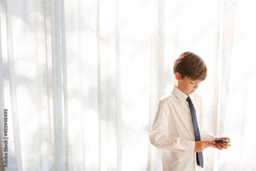 Fototapeta premium Boy in shirt and tie holding smartphone