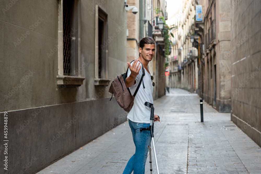 Young latin man with crutches visiting the city