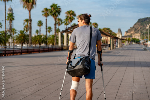 Young latin man with crutches walking in the city