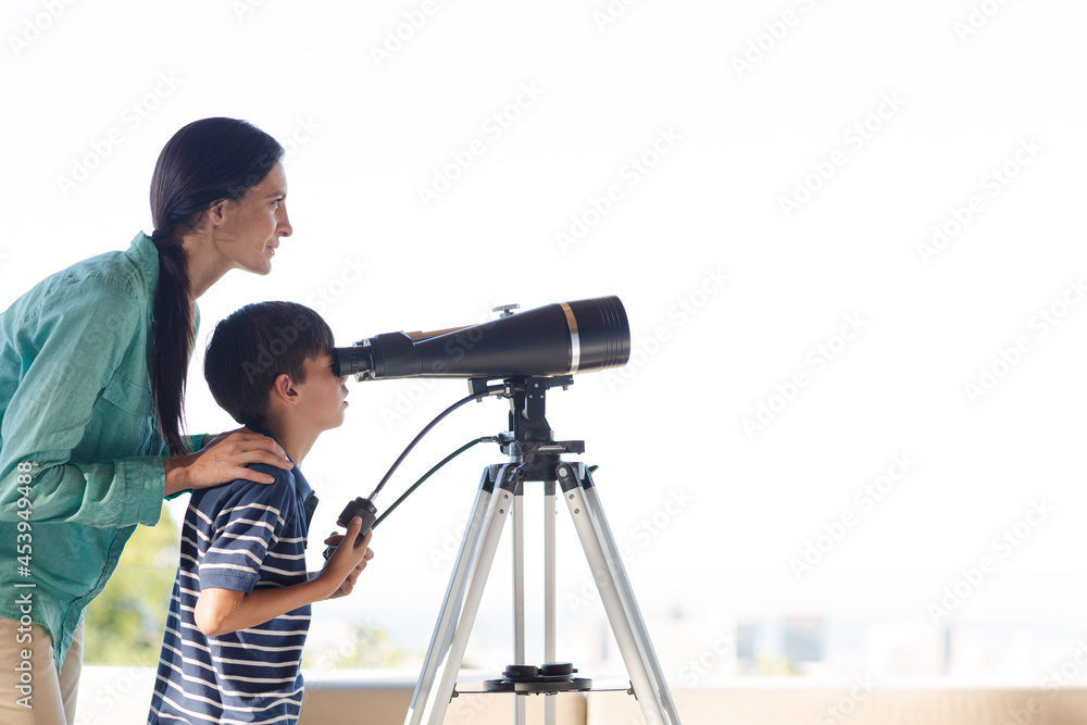 Mother and son using telescope outdoors