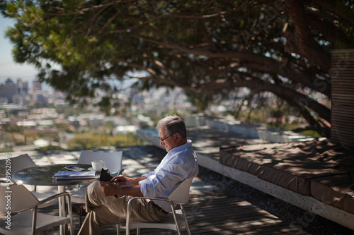 Older man using tablet computer outdoors