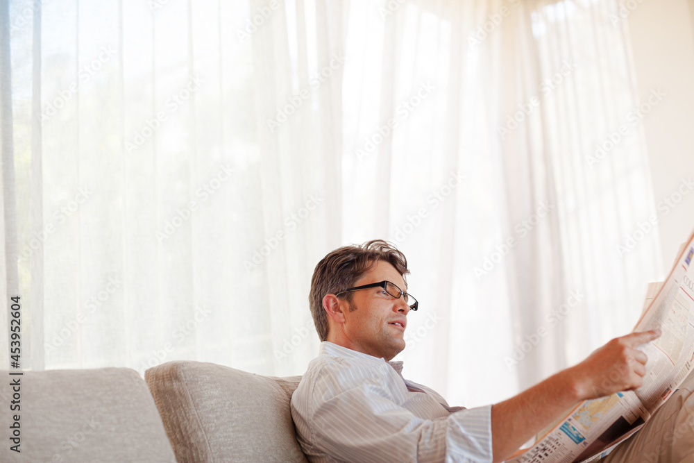 Fototapeta premium Man reading newspaper on sofa
