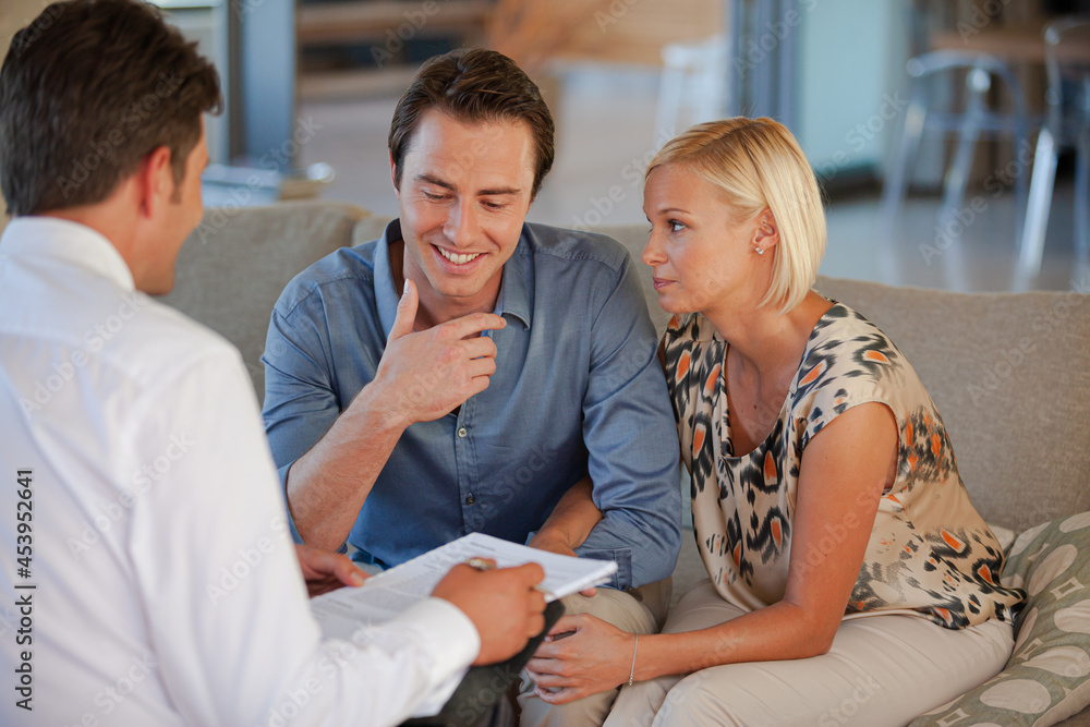 Financial advisor talking to couple on sofa Financial advisor talking to couple on sofa