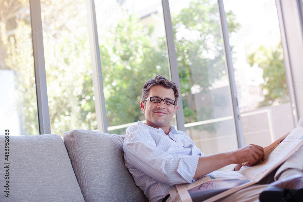 Man reading newspaper on sofa Man reading newspaper on sofa