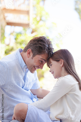 Father and daughter touching foreheads outdoors