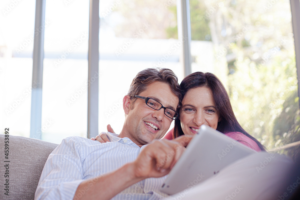 Couple using tablet computer on sofa Couple using tablet computer on sofa