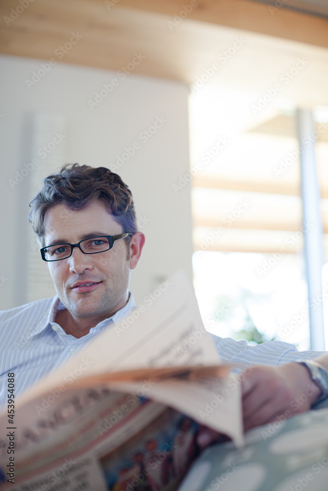 Fototapeta premium Man reading newspaper on sofa