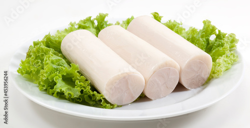 Palmito em toletes sob alface no prato em fundo branco para recorte.
