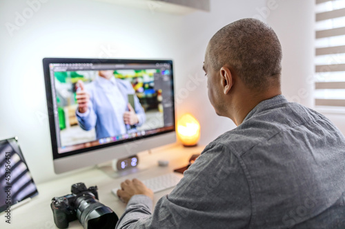 Work in an agency. Work from home as a freelancer. Editing and correction of photos in the living room in the apartment in casual clothes. Photographer and graphic designer