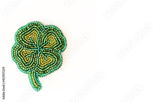 beaded clover with four leaves on a white background. beaded brooch. accessory for ladies. top view, flat lay