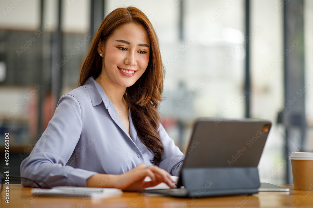 Portrait of smiling beautiful business asian woman working in modern office desk using tablet laptop computer, Business people employee freelance online marketing e-commerce telemarketing concept. Portrait of smiling beautiful business asian woman working in modern office desk using tablet laptop computer, Business people employee freelance online marketing e-commerce telemarketing concept.