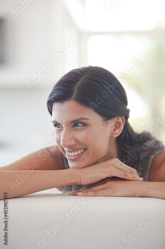 Woman resting chin in hands on sofa