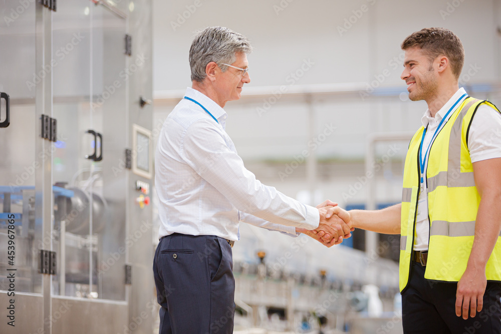 Supervisor and worker shaking hands in factory Supervisor and worker shaking hands in factory