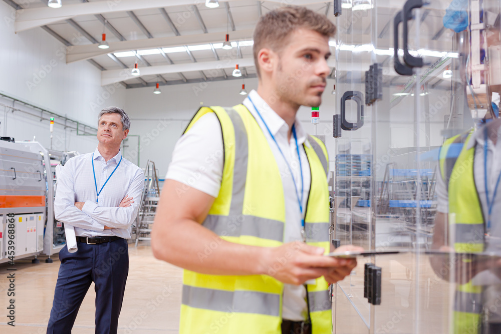 Supervisor watching worker in factory Supervisor watching worker in factory