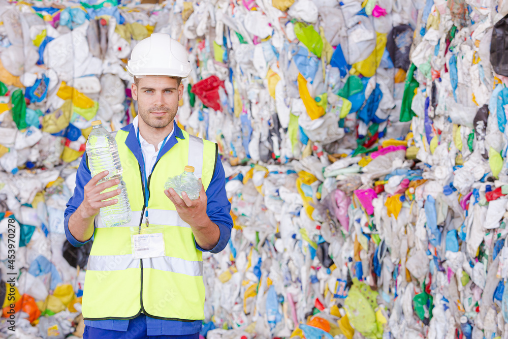 Worker holding compacted plastic bottle in recycling center