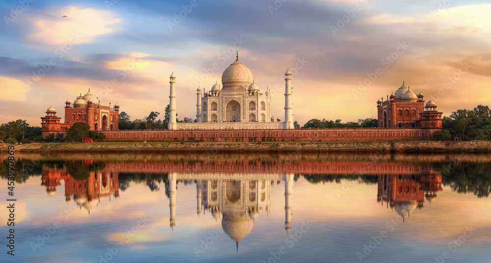 Taj Mahal Agra India at sunset with moody sky and water reflections on river Yamuna.	