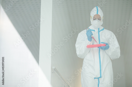 Scientist in clean suit with pipette and tray