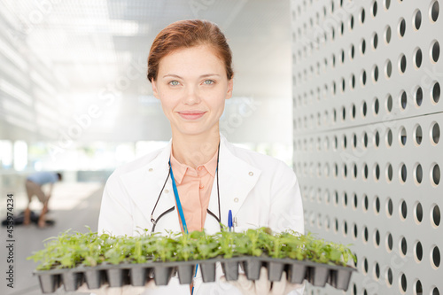 Portrait of botanist holding tray of plant saplings photo