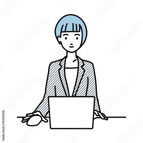 デスクで座ってPCを使っているスーツの女性
