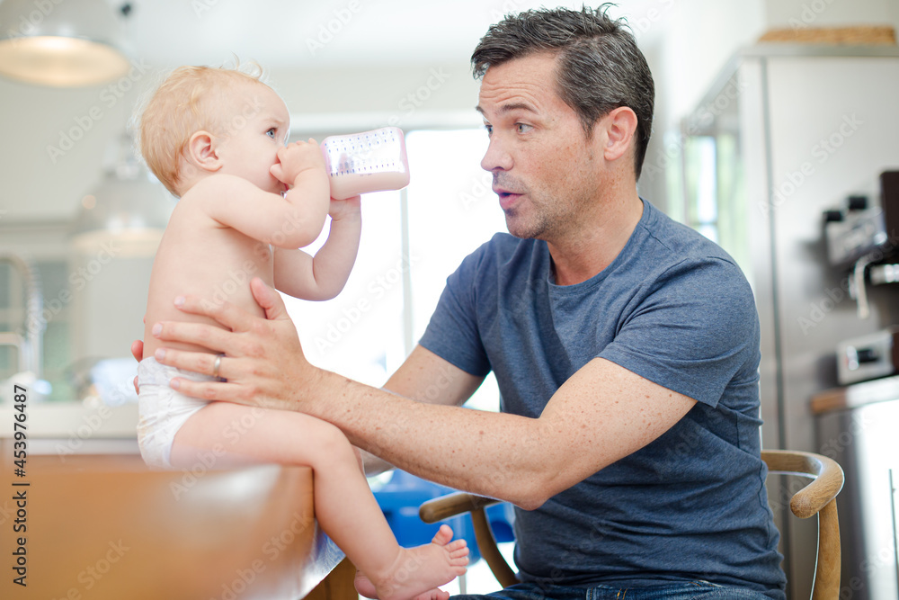 Obraz premium Father feeding baby in kitchen