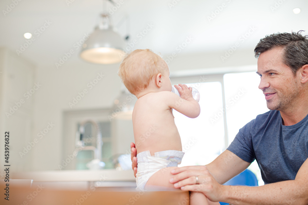 Fototapeta premium Father feeding baby in kitchen