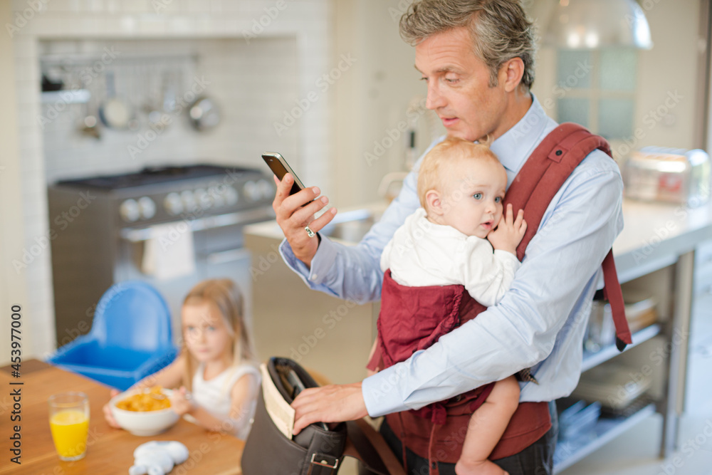 Father holding baby and checking cell phone Father holding baby and checking cell phone