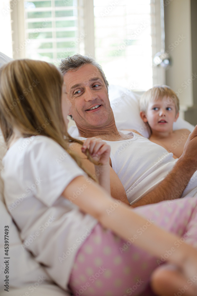 Father and children using digital tablet on bed Father and children using digital tablet on bed
