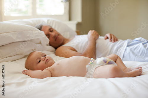Father and baby laying on bed