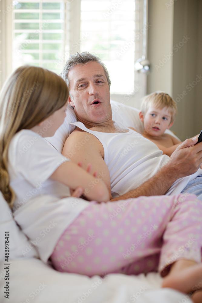 Father and children using digital tablet on bed Father and children using digital tablet on bed