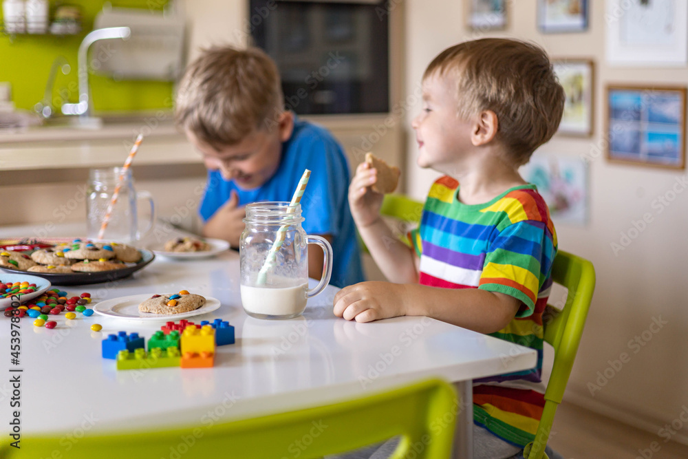 Funny male brothers eat cookies with round multi-colored sweets m&m and drink milk. Funny male brothers eat cookies with round multi-colored sweets m&m and drink milk.