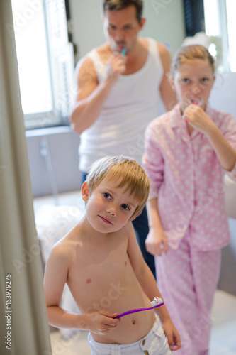 Father and children brushing teeth in bathroom