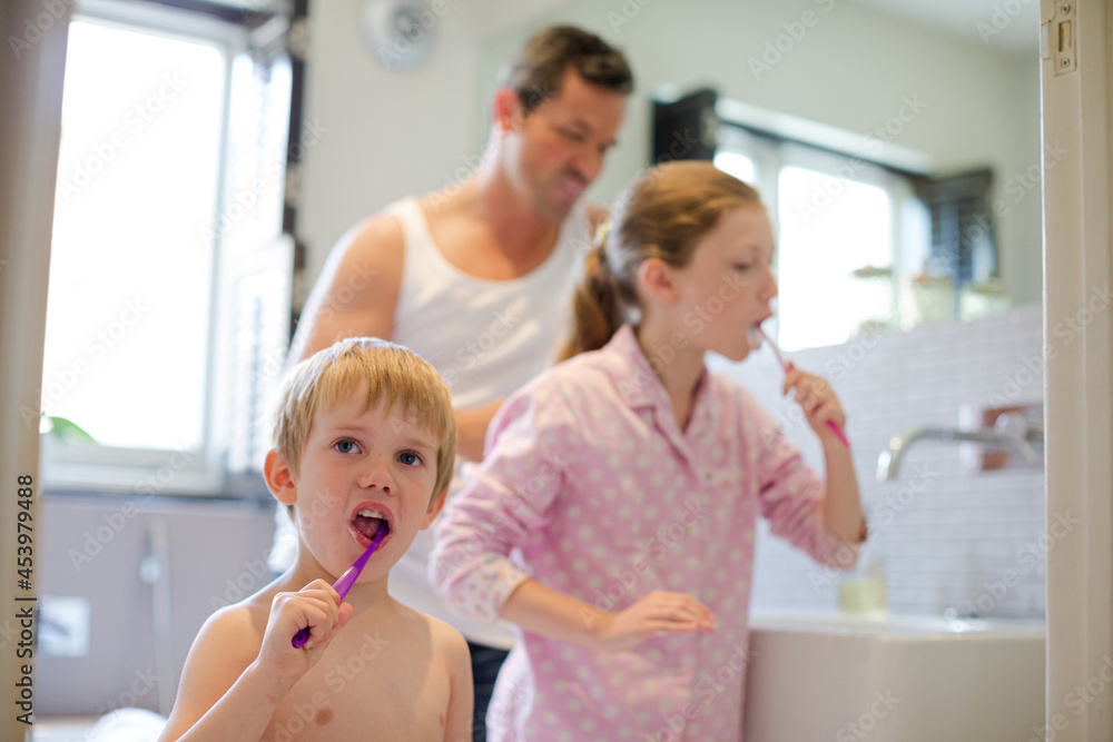 Father and children brushing teeth in bathroom Father and children brushing teeth in bathroom