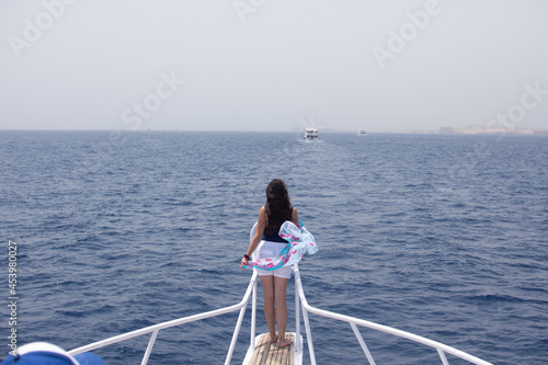 young beautiful woman on the bow of a yacht looks at the sea. yacht trip in Egypt on the red sea.