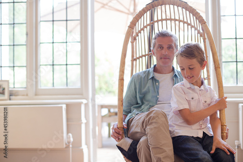 Father and son sitting in wicker chair