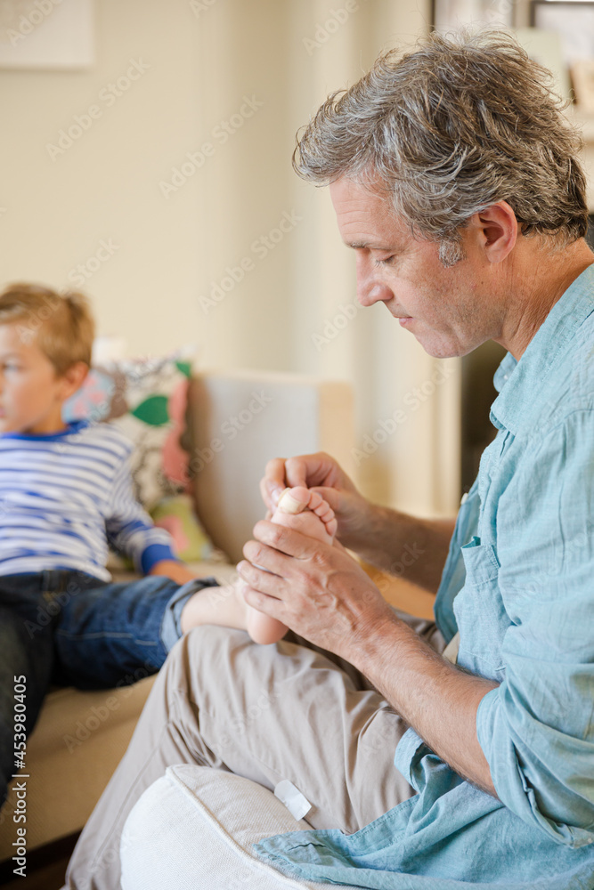 Father bandaging son's foot Father bandaging son's foot