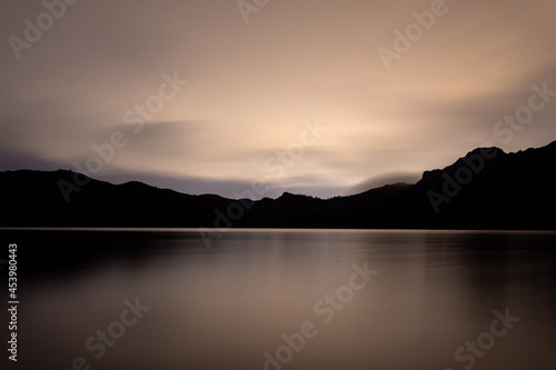 sunset over the lake mirror effect mountains silhouette © Juanfer