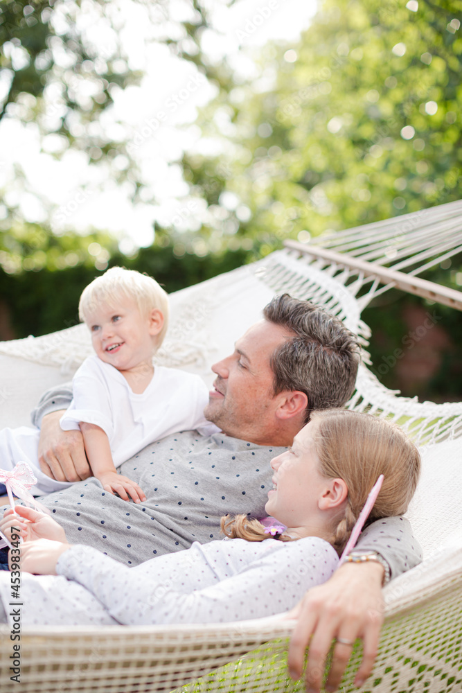 Obraz premium Father and children laying in hammock outdoors