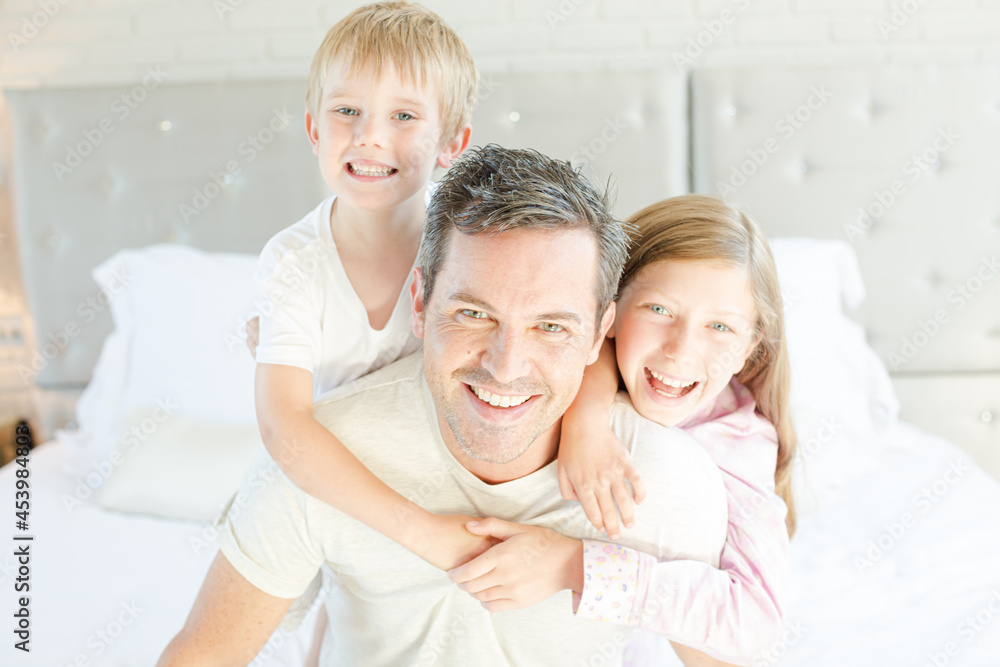 Father and children hugging in bedroom Father and children hugging in bedroom