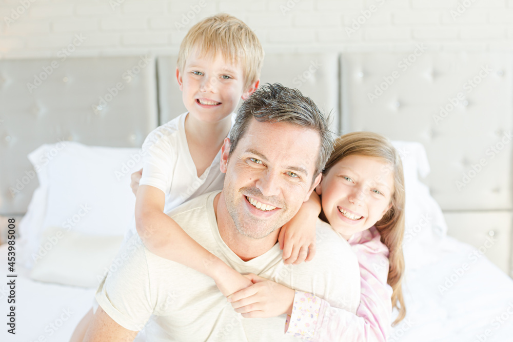 Father and children hugging in bedroom Father and children hugging in bedroom