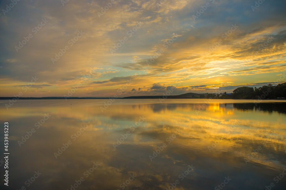 Obraz premium beautiful landscape of the water surface of the lake on a summer morning with light clouds in the sky reflecting in the water