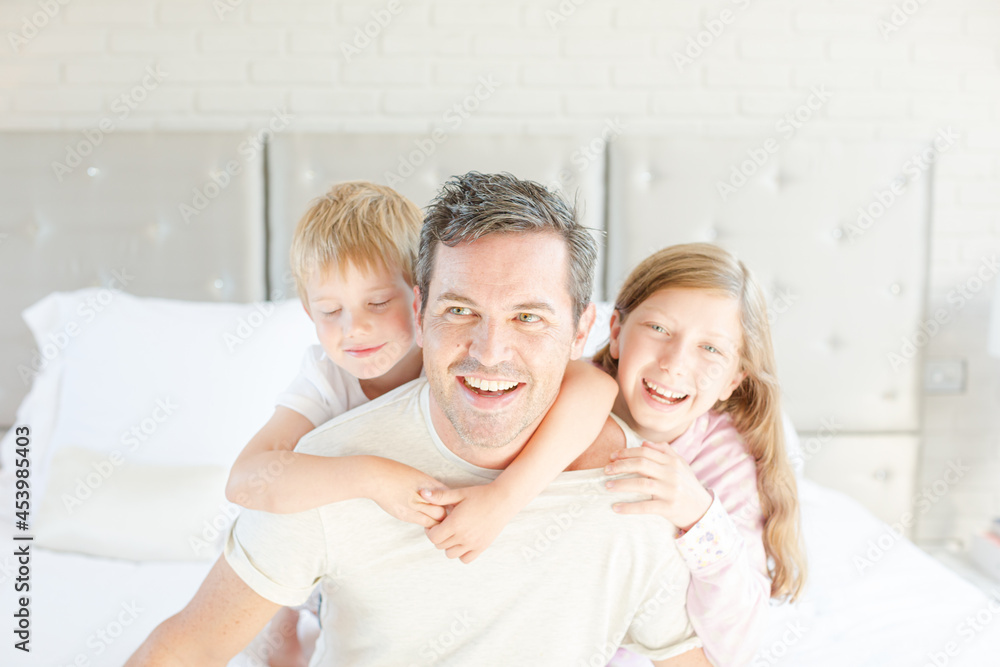 Father and children hugging in bedroom Father and children hugging in bedroom