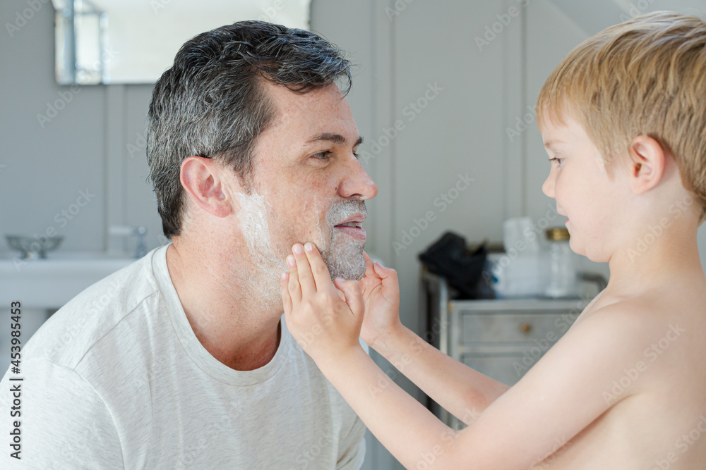 Boy rubbing shaving cream on father's face Boy rubbing shaving cream on father's face