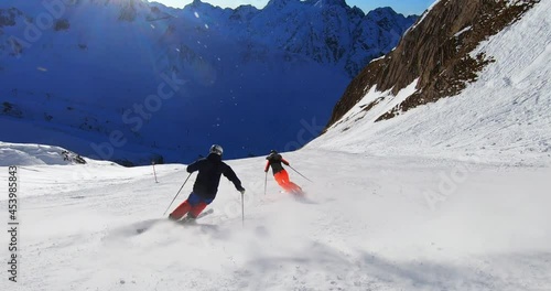 Ski show of a young couple on a steep ski slope in a ski resort in Austria, Tyrol. Cinematic follow camera skiing in nice rhythmic short ski turns with great skiing style in amazing mountain landscape photo