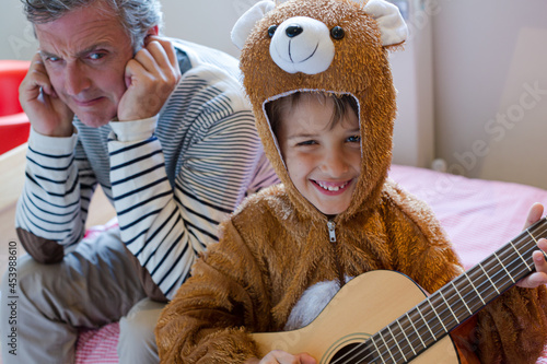 Father covers his ears when son playing guitar