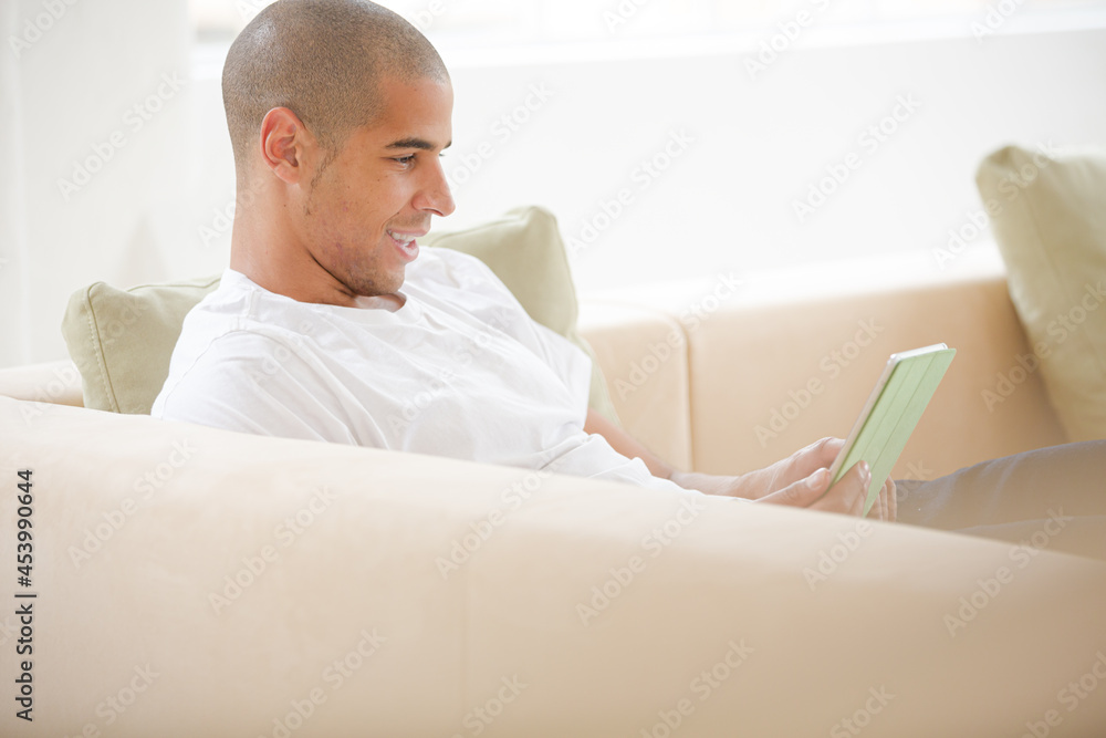 Obraz premium Man using digital tablet on sofa