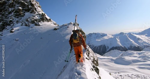 Mountain climber hiking in deep snow on a ridge at a mountain peak. Extreme mountaineering in winter with skis in wonderful winter alpine landscape and lots of fresh snow. Tyrolean mountaineering 4K photo