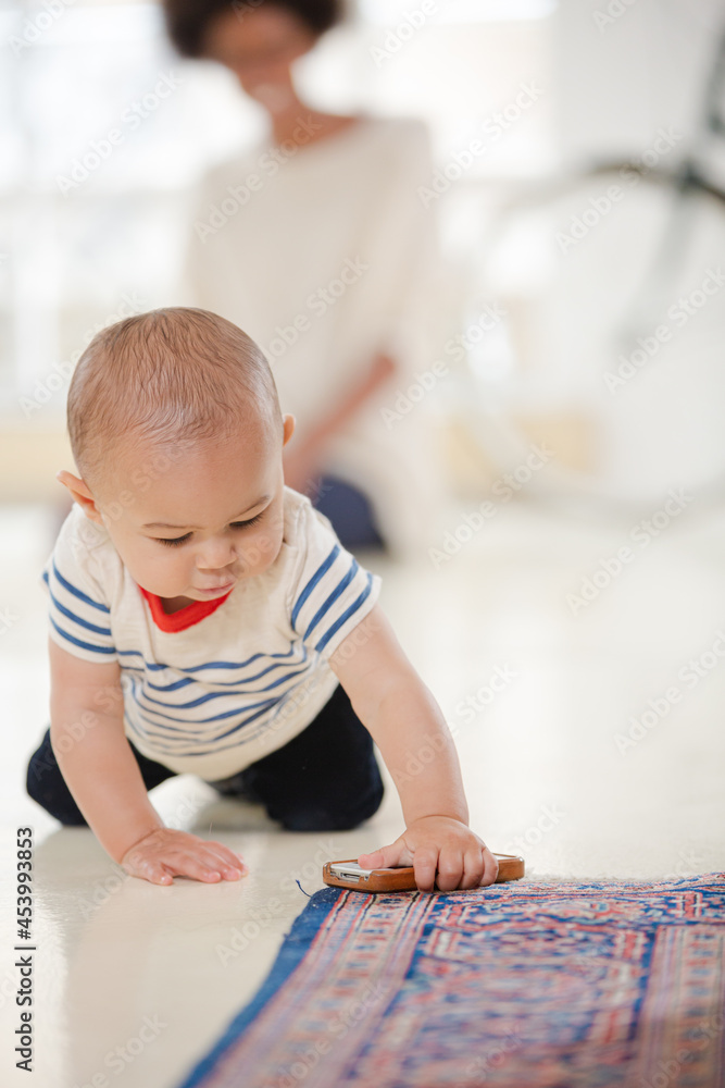 Mother watching baby boy crawl in living room Mother watching baby boy crawl in living room