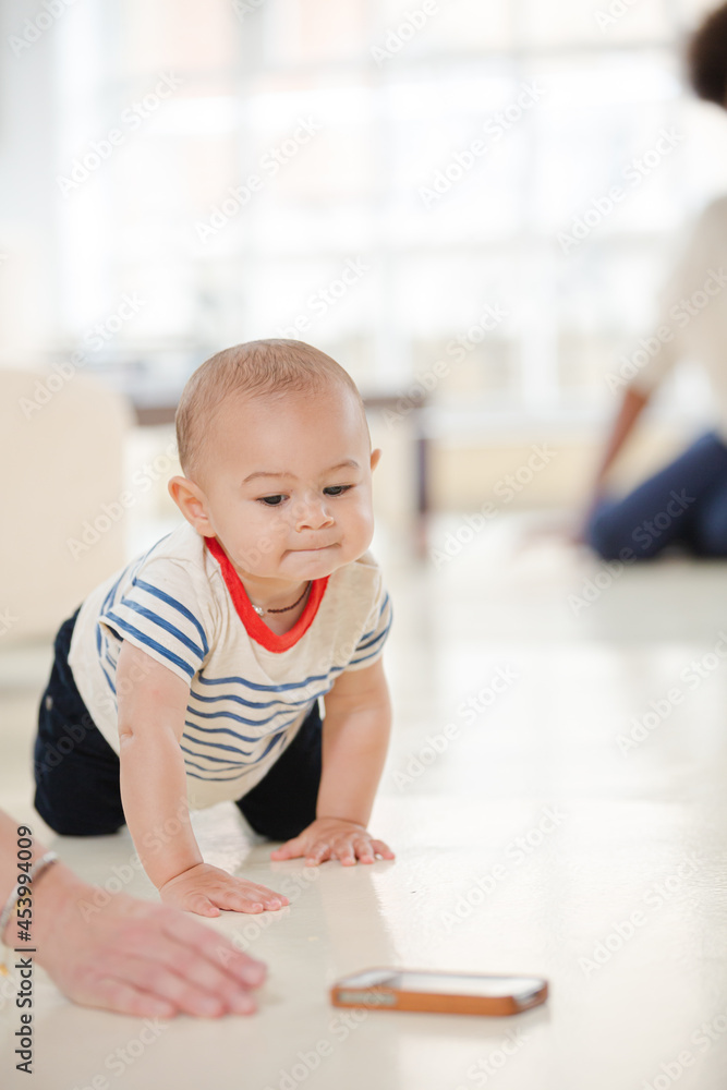 Mother watching baby boy crawl in living room Mother watching baby boy crawl in living room