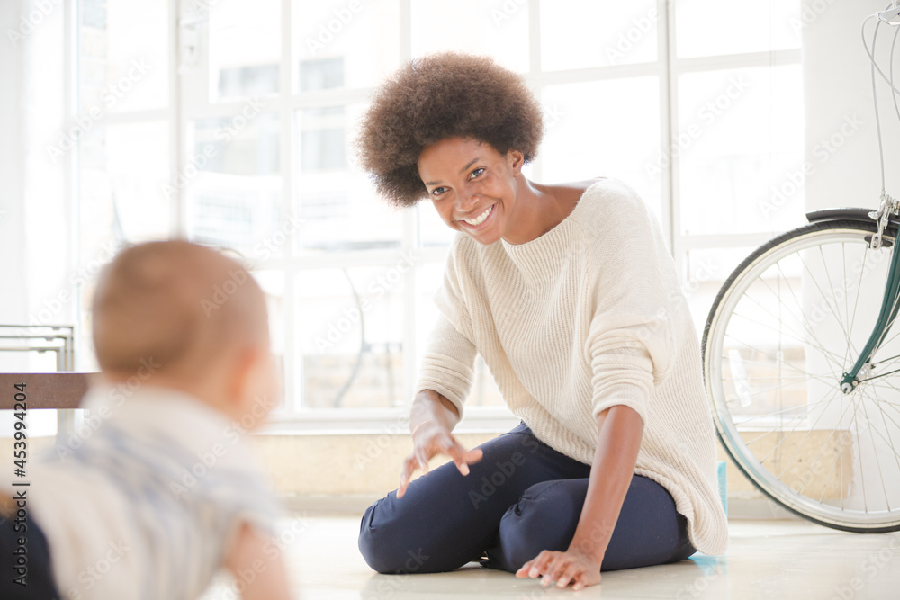 Fototapeta premium Mother watching baby boy crawl on floor